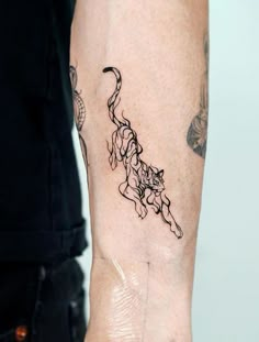 a woman's arm with a tattoo on it that has a cat in the middle