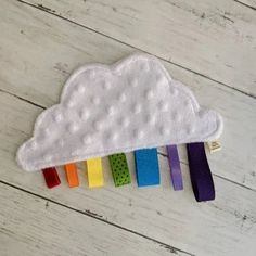 a small white cloud with rainbows on the side sitting on top of a wooden floor