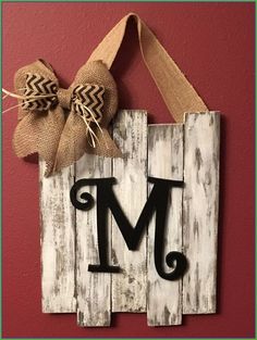 a wooden sign with the letter m on it and a burlocked bow