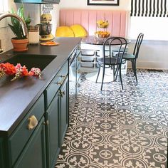 a kitchen with black counter tops and white tile flooring, along with green cabinets