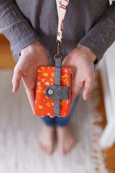 a person holding an orange and gray case with a cross on the front in their hands