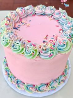 a pink cake with sprinkles and frosting on it's side