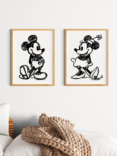 two black and white mickey mouse prints hanging on the wall above a bed with pillows