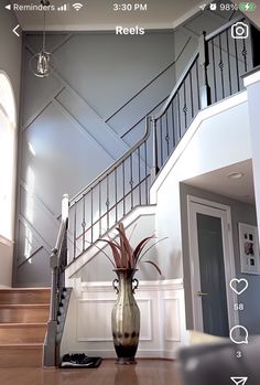 a vase sitting on top of a wooden floor next to a stair case in a house