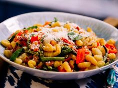 a white bowl filled with pasta and vegetables covered in parmesan cheese on top