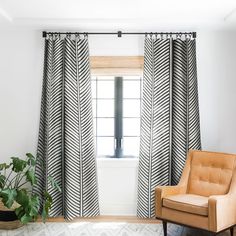 a chair sitting in front of a window next to a potted plant on top of a rug