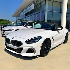 two white sports cars are parked in front of a bmw dealership