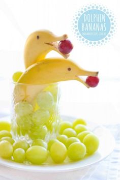 two bananas and grapes in a glass on a white plate with the words dolphin banana's