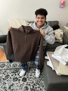 a man holding up a brown jacket in his living room