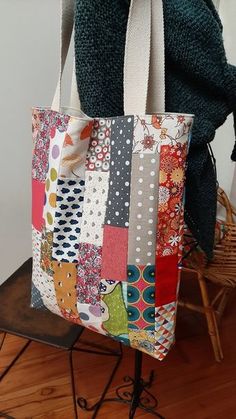 a multicolored tote bag sitting on top of a wooden table next to a chair