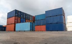 there are many containers stacked on top of each other in the middle of an empty lot