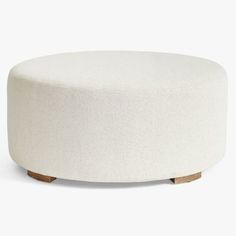 a white round ottoman with wooden legs