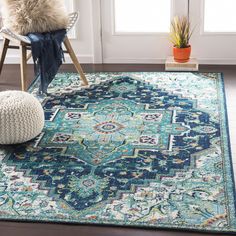 a blue area rug with an ornate design on the bottom and sides, in front of a window