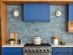 a kitchen with blue cabinets and white counter tops is pictured in this image, there are wooden shelves on either side of the stove