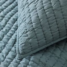 a close up view of a bed with blue sheets and pillows