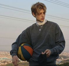 a young man holding a basketball on top of a hill with power lines in the background