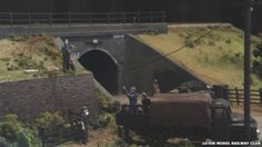 people standing on the side of a road next to a truck with a tunnel in it