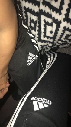 a person with their foot on the ground wearing adidas sweatpants and holding onto his leg