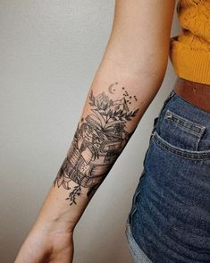 a woman's arm with a tattoo on it and flowers in the middle of her arm