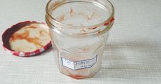 an empty glass jar sitting on top of a table next to a red and white container