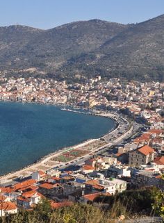 an aerial view of a city next to the ocean with mountains in the back ground