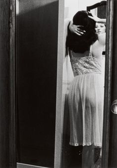 a woman standing in front of a mirror holding her hair