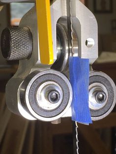 a pair of rollers attached to a machine with a blue piece of paper hanging from it