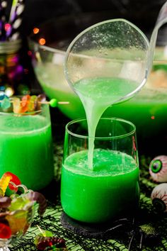 green liquid being poured into two glasses filled with candy