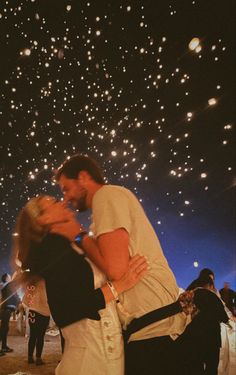 a man and woman kissing in front of fireworks on the night sky with their arms around each other