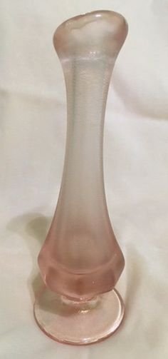 a pink glass vase sitting on top of a white sheet