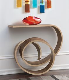 a wooden table with an abstract sculpture on it's top and three vases behind it