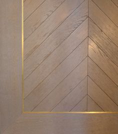 an empty wooden door with gold trim on the bottom and side panel, in a herringbone pattern