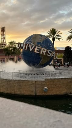 a large blue and white globe with the word universal on it in front of a building