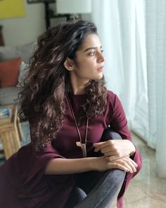 a woman sitting on top of a chair next to a window