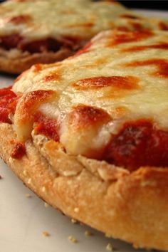 two pizzas sitting next to each other on top of a white tablecloth covered counter