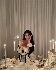 a woman sitting at a table with candles in front of her