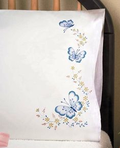 a white pillow with blue butterflies on it in a crib next to a pink bow