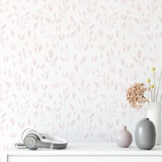 two vases with flowers in them sit on a dresser against a wallpapered background