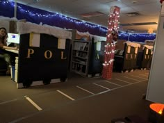 a woman sitting at a desk in an office decorated for christmas with lights on the ceiling