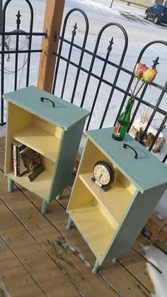 two side tables with books and magazines on them in front of a black iron fence