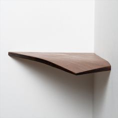 a wooden shelf mounted to the side of a white wall with no one on it