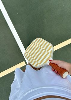 a person holding a hot dog on top of a tennis court