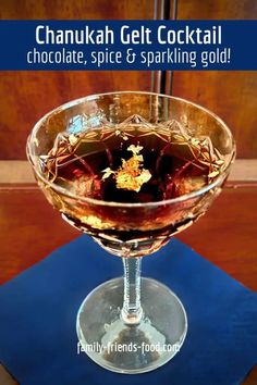 a glass filled with liquid sitting on top of a blue table cloth next to a wooden wall