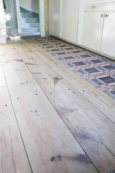 an empty room with wooden floors and white cabinets