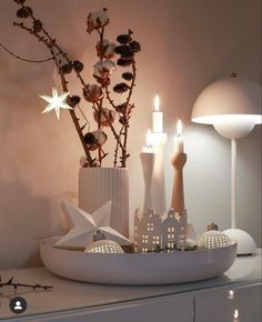 a white bowl with some candles in it on top of a table next to a vase