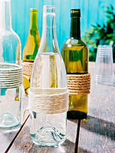 several empty glass bottles sitting on top of a wooden table with rope wrapped around them