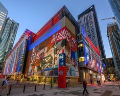 people are walking in front of a building that has advertisements on the side of it