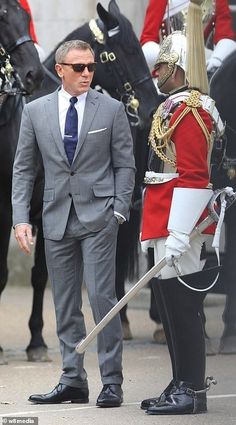 a man in a suit and tie standing next to a guard