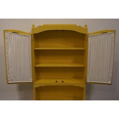 an open yellow bookcase with white curtains