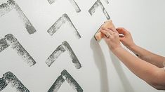 a woman is painting a wall with black and white letters on the wall behind her